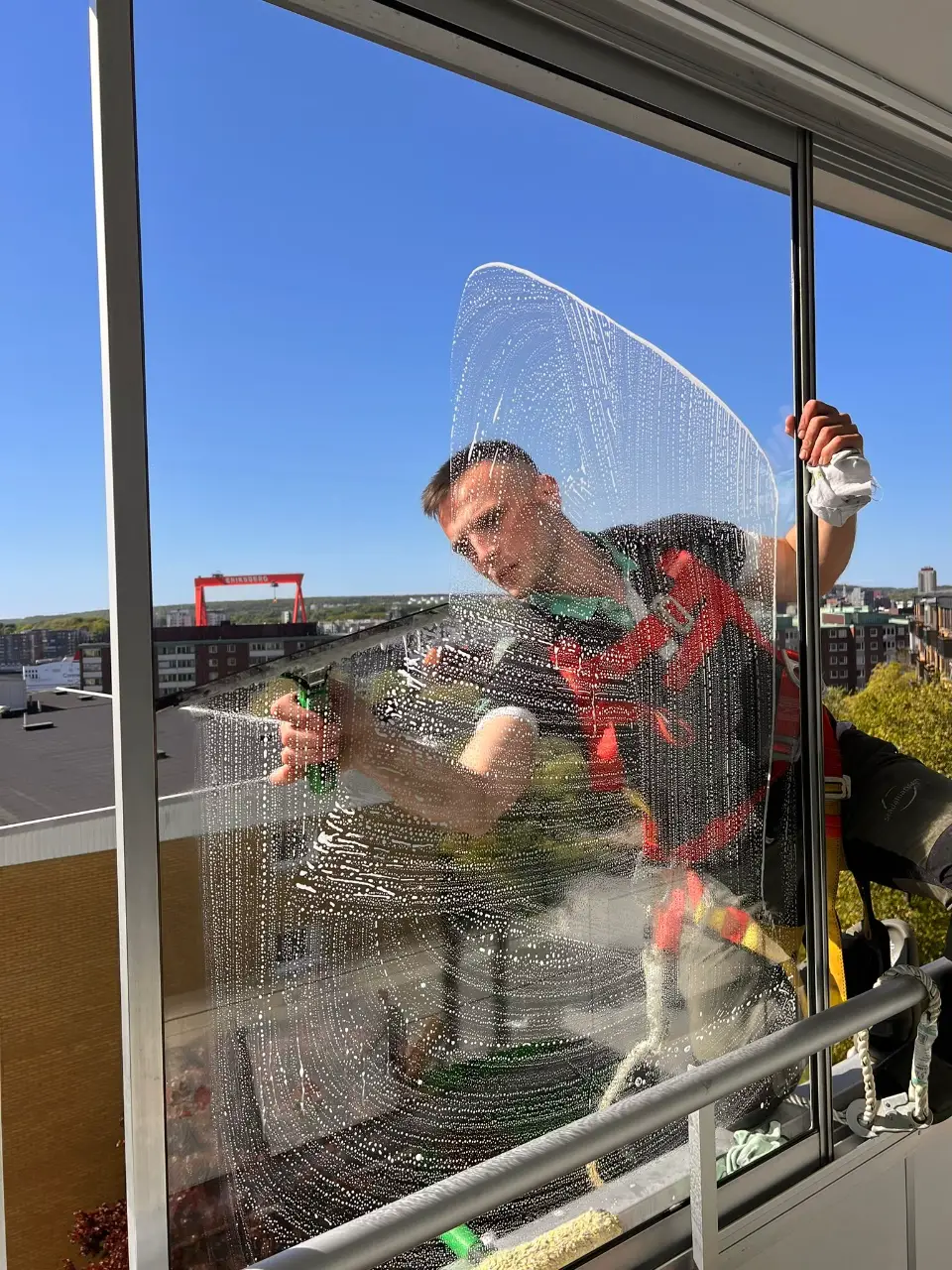 Fönsterputsare från Städalliansen rengör ett stort glasparti